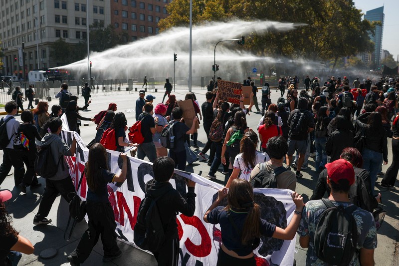 A demonstrator throws an object as a water cannon is used during a protest against the Chilean government's budget cuts to education, in Santiago, Chile, March 26, 2026. REUTERS/Pablo Sanhueza
