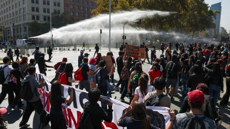 A demonstrator throws an object as a water cannon is used during a protest against the Chilean government's budget cuts to education, in Santiago, Chile, March 26, 2026. REUTERS/Pablo Sanhueza