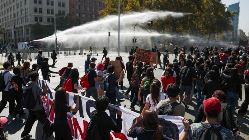 A demonstrator throws an object as a water cannon is used during a protest against the Chilean government's budget cuts to education, in Santiago, Chile, March 26, 2026. REUTERS/Pablo Sanhueza