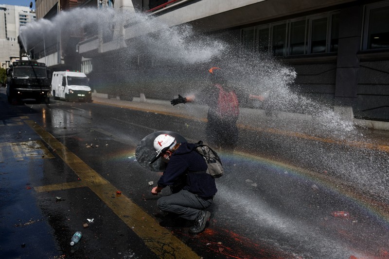 A demonstrator throws an object as a water cannon is used during a protest against the Chilean government's budget cuts to education, in Santiago, Chile, March 26, 2026. REUTERS/Pablo Sanhueza