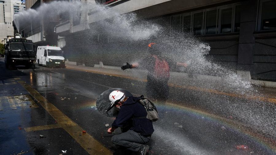 A demonstrator throws an object as a water cannon is used during a protest against the Chilean government's budget cuts to education, in Santiago, Chile, March 26, 2026. REUTERS/Pablo Sanhueza