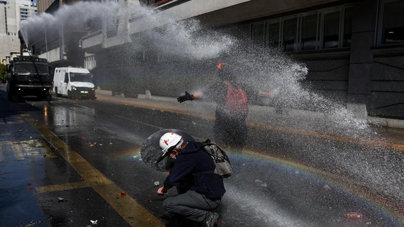 A demonstrator throws an object as a water cannon is used during a protest against the Chilean government's budget cuts to education, in Santiago, Chile, March 26, 2026. REUTERS/Pablo Sanhueza