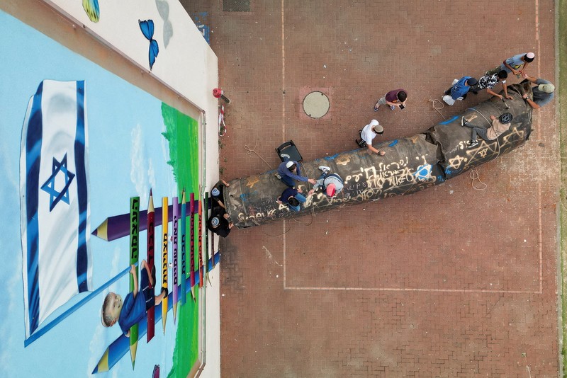 Seorang gadis berpose untuk foto di samping sisa-sisa rudal yang tertancap di tanah yang ditemukan di desa Kifl Haris, dekat Nablus di Tepi Barat yang diduduki Israel, 24 Maret 2026. (REUTERS/Mohammed Torokman/File Photo)