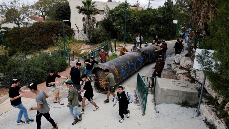 Seorang gadis berpose untuk foto di samping sisa-sisa rudal yang tertancap di tanah yang ditemukan di desa Kifl Haris, dekat Nablus di Tepi Barat yang diduduki Israel, 24 Maret 2026. (REUTERS/Mohammed Torokman/File Photo)