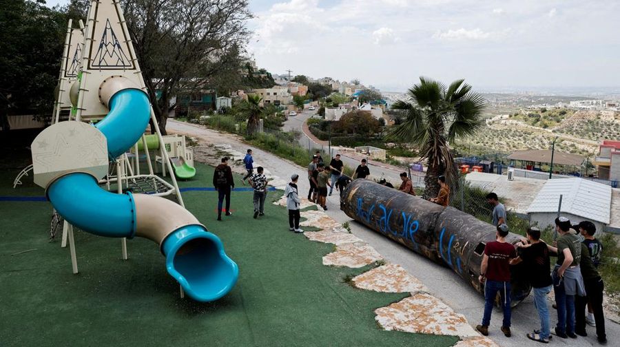 Seorang gadis berpose untuk foto di samping sisa-sisa rudal yang tertancap di tanah yang ditemukan di desa Kifl Haris, dekat Nablus di Tepi Barat yang diduduki Israel, 24 Maret 2026. (REUTERS/Mohammed Torokman/File Photo)