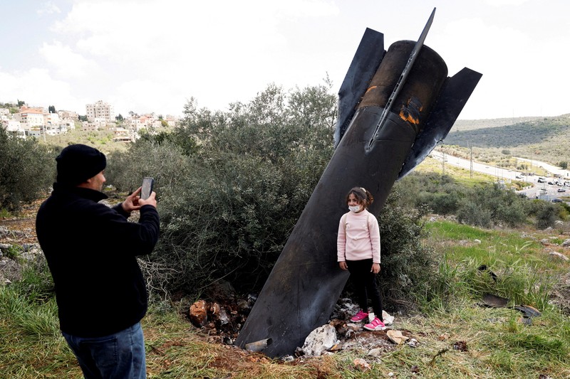 Seorang gadis berpose untuk foto di samping sisa-sisa rudal yang tertancap di tanah yang ditemukan di desa Kifl Haris, dekat Nablus di Tepi Barat yang diduduki Israel, 24 Maret 2026. (REUTERS/Mohammed Torokman/File Photo)