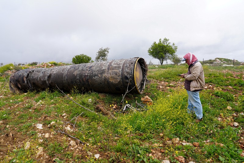 Seorang gadis berpose untuk foto di samping sisa-sisa rudal yang tertancap di tanah yang ditemukan di desa Kifl Haris, dekat Nablus di Tepi Barat yang diduduki Israel, 24 Maret 2026. (REUTERS/Mohammed Torokman/File Photo)