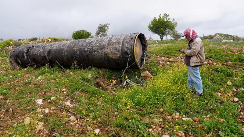Seorang gadis berpose untuk foto di samping sisa-sisa rudal yang tertancap di tanah yang ditemukan di desa Kifl Haris, dekat Nablus di Tepi Barat yang diduduki Israel, 24 Maret 2026. (REUTERS/Mohammed Torokman/File Photo)