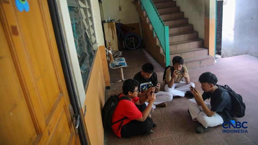 Sejumlah anak memainkan ponsel mereka sesuai pulang sekolah di Jakarta, Senin (30/3/2026). Pemerintah resmi melarang anak di bawah usia 16 tahun menggunakan media sosial mulai 28 Maret 2026 berdasarkan Peraturan Menteri Komunikasi dan Digital Nomor 9 Tahun 2026, yang merupakan turunan dari PP Tunas. (CNBC Indonesia/Faisal Rahman)