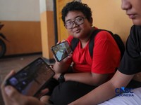 Sejumlah anak memainkan ponsel mereka sesuai pulang sekolah di Jakarta, Senin (30/3/2026). Pemerintah resmi melarang anak di bawah usia 16 tahun menggunakan media sosial mulai 28 Maret 2026 berdasarkan Peraturan Menteri Komunikasi dan Digital Nomor 9