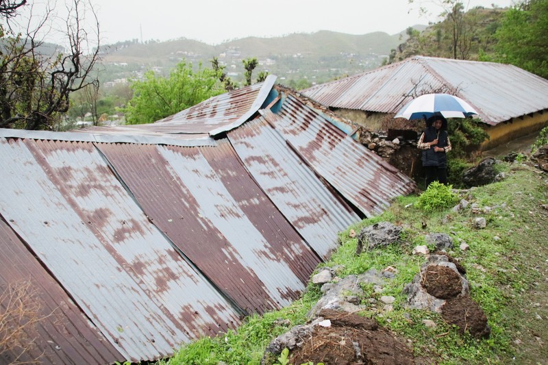 Seseorang berjalan melewati atap sebuah rumah yang runtuh setelah hujan lebat di Abbottabad, provinsi Khyber Pakhtunkhwa di Pakistan, 30 Maret 2026. (REUTERS/Sultan Dogar)