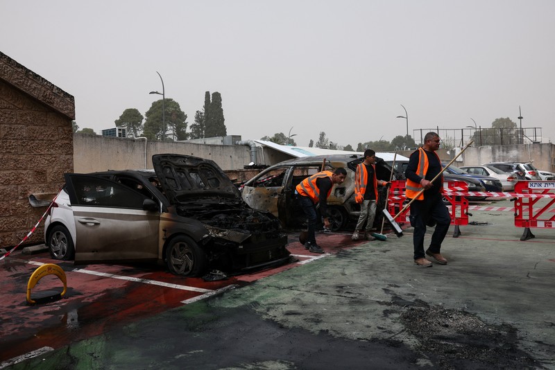 Personel darurat Israel bekerja di samping kendaraan yang hancur di lokasi dampak proyektil, di tengah meningkatnya permusuhan antara Israel dan Hizbullah, sementara konflik AS-Israel dengan Iran terus berlanjut, di Kiryat Ata, Israel utara, 3 April 2026. (REUTERS/Shir Torem)