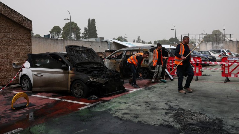 Personel darurat Israel bekerja di samping kendaraan yang hancur di lokasi dampak proyektil, di tengah meningkatnya permusuhan antara Israel dan Hizbullah, sementara konflik AS-Israel dengan Iran terus berlanjut, di Kiryat Ata, Israel utara, 3 April 2026. (REUTERS/Shir Torem)