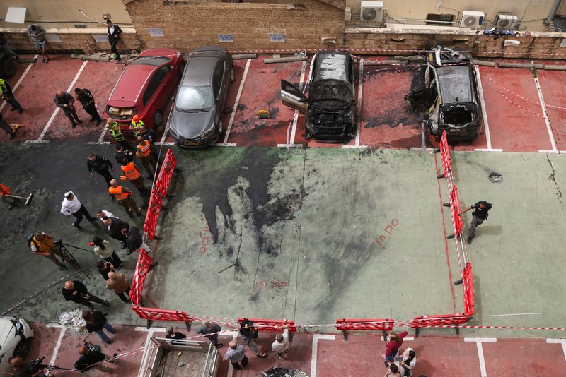 Personel darurat Israel bekerja di samping kendaraan yang hancur di lokasi dampak proyektil, di tengah meningkatnya permusuhan antara Israel dan Hizbullah, sementara konflik AS-Israel dengan Iran terus berlanjut, di Kiryat Ata, Israel utara, 3 April 2026. (REUTERS/Shir Torem)