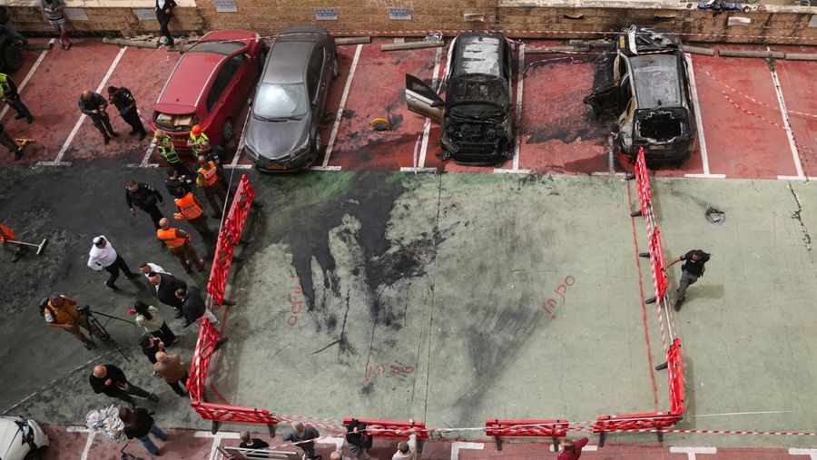 Personel darurat Israel bekerja di samping kendaraan yang hancur di lokasi dampak proyektil, di tengah meningkatnya permusuhan antara Israel dan Hizbullah, sementara konflik AS-Israel dengan Iran terus berlanjut, di Kiryat Ata, Israel utara, 3 April 2026. (REUTERS/Shir Torem)