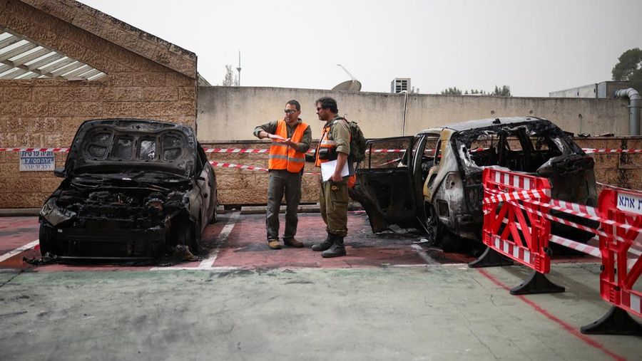 Personel darurat Israel bekerja di samping kendaraan yang hancur di lokasi dampak proyektil, di tengah meningkatnya permusuhan antara Israel dan Hizbullah, sementara konflik AS-Israel dengan Iran terus berlanjut, di Kiryat Ata, Israel utara, 3 April 2026. (REUTERS/Shir Torem)