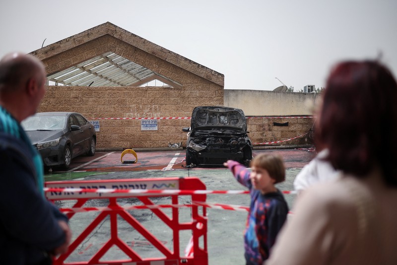 Personel darurat Israel bekerja di samping kendaraan yang hancur di lokasi dampak proyektil, di tengah meningkatnya permusuhan antara Israel dan Hizbullah, sementara konflik AS-Israel dengan Iran terus berlanjut, di Kiryat Ata, Israel utara, 3 April 2026. (REUTERS/Shir Torem)