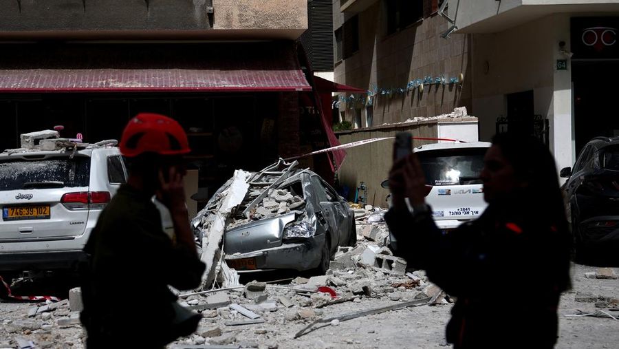 Gambar dari drone yang memperlihatkan personel darurat di lokasi terdampak di lingkungan perumahan, setelah dihujani rudal yang diluncurkan dari Iran, di tengah konflik AS-Israel dengan Iran, di Israel tengah, 6 April 2026. (REUTERS/Roei Kastro)