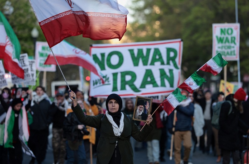 Seorang demonstran membawa potret mendiang Pemimpin Tertinggi Iran Ayatollah Ali Khamenei selama protes menentang aksi militer di Iran dekat Gedung Putih di Washington, D.C., AS, 8 April 2026. (REUTERS/Evelyn Hockstein)