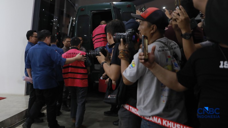 Petugas mendampingi tersangka perkara dugaan pengadaan minyak mentah dan produk kilang Irawan Prakoso (tengah) seusai menjalani pemeriksaan di Kejaksaan Agung, Jakarta, Kamis (9/4/2026). Kejaksaan Agung menetapkan tujuh tersangka dalam kasus dugaan korupsi pengadaan minyak mentah dan produk kilang di Pertamina Energy Trading Limited (Petral) atau Pertamina Energy Services (PES) Pte Ltd. (CNBC Indonesia/Muhammad Sabki)