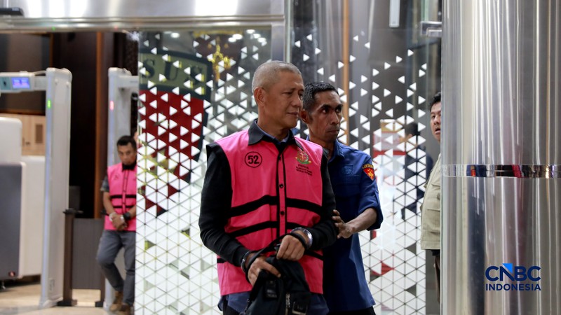 Petugas mendampingi tersangka perkara dugaan pengadaan minyak mentah dan produk kilang Irawan Prakoso (tengah) seusai menjalani pemeriksaan di Kejaksaan Agung, Jakarta, Kamis (9/4/2026). Kejaksaan Agung menetapkan tujuh tersangka dalam kasus dugaan korupsi pengadaan minyak mentah dan produk kilang di Pertamina Energy Trading Limited (Petral) atau Pertamina Energy Services (PES) Pte Ltd. (CNBC Indonesia/Muhammad Sabki)