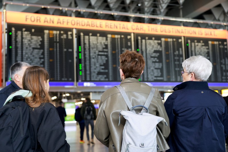 Orang-orang melihat papan informasi yang menampilkan penerbangan, yang sebagian besar dibatalkan, selama pemogokan oleh serikat UFO, yang mewakili awak kabin Lufthansa, di Bandara Frankfurt, Jerman, 10 April 2026. (REUTERS/Heiko Becker)