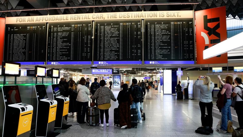 Orang-orang melihat papan informasi yang menampilkan penerbangan, yang sebagian besar dibatalkan, selama pemogokan oleh serikat UFO, yang mewakili awak kabin Lufthansa, di Bandara Frankfurt, Jerman, 10 April 2026. (REUTERS/Heiko Becker)