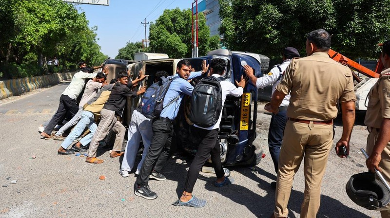 Seorang wanita berjalan melewati deretan mobil hangus yang berjejer di luar Maruti Suzuki Car Center, yang rusak selama protes pekerja, setelah para pekerja pabrik menuntut kenaikan upah, di tengah melonjaknya biaya hidup akibat gangguan yang disebabkan oleh konflik AS-Israel dengan Iran, di Noida, kota pusat industri India di negara bagian Uttar Pradesh, India, 13 April 2026. (REUTERS/Anushree Fadnavis)