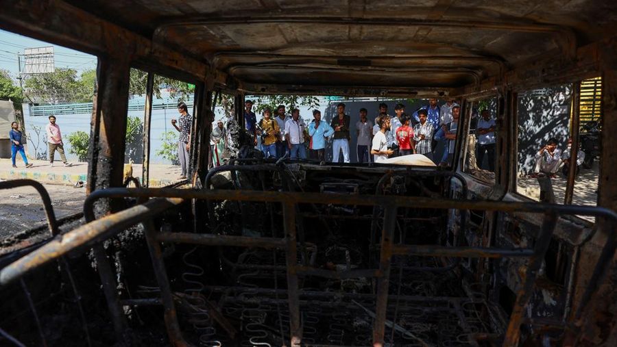 Seorang wanita berjalan melewati deretan mobil hangus yang berjejer di luar Maruti Suzuki Car Center, yang rusak selama protes pekerja, setelah para pekerja pabrik menuntut kenaikan upah, di tengah melonjaknya biaya hidup akibat gangguan yang disebabkan oleh konflik AS-Israel dengan Iran, di Noida, kota pusat industri India di negara bagian Uttar Pradesh, India, 13 April 2026. (REUTERS/Anushree Fadnavis)
