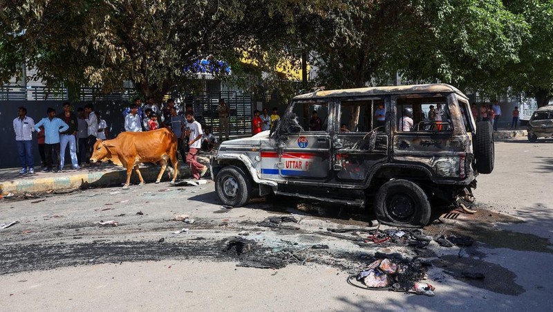 Seorang wanita berjalan melewati deretan mobil hangus yang berjejer di luar Maruti Suzuki Car Center, yang rusak selama protes pekerja, setelah para pekerja pabrik menuntut kenaikan upah, di tengah melonjaknya biaya hidup akibat gangguan yang disebabkan oleh konflik AS-Israel dengan Iran, di Noida, kota pusat industri India di negara bagian Uttar Pradesh, India, 13 April 2026. (REUTERS/Anushree Fadnavis)