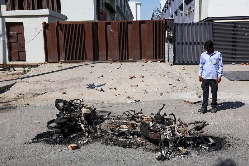 Seorang wanita berjalan melewati deretan mobil hangus yang berjejer di luar Maruti Suzuki Car Center, yang rusak selama protes pekerja, setelah para pekerja pabrik menuntut kenaikan upah, di tengah melonjaknya biaya hidup akibat gangguan yang disebabkan oleh konflik AS-Israel dengan Iran, di Noida, kota pusat industri India di negara bagian Uttar Pradesh, India, 13 April 2026. (REUTERS/Anushree Fadnavis)