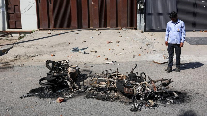 Seorang wanita berjalan melewati deretan mobil hangus yang berjejer di luar Maruti Suzuki Car Center, yang rusak selama protes pekerja, setelah para pekerja pabrik menuntut kenaikan upah, di tengah melonjaknya biaya hidup akibat gangguan yang disebabkan oleh konflik AS-Israel dengan Iran, di Noida, kota pusat industri India di negara bagian Uttar Pradesh, India, 13 April 2026. (REUTERS/Anushree Fadnavis)