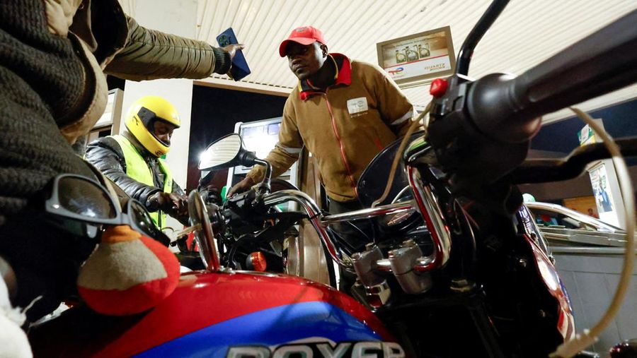 A fuel pump attendant confirms a mobile phone payment as he fuels a motorcycle taxi at a TotalEnergies petrol station ahead of an announced fuel price hike, as fuel costs rise amid global disruptions caused by the Iran war, in Nairobi, Kenya April 14, 2026. REUTERS/Thomas Mukoya