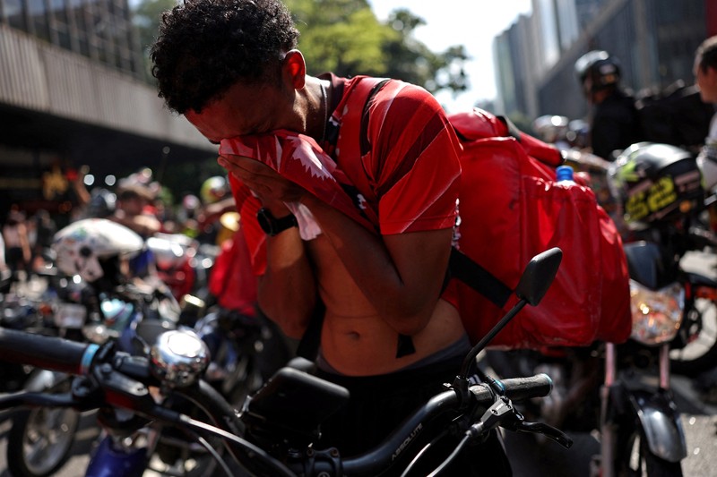 Para pekerja pengiriman barang melakukan protes menuntut perbaikan kondisi kerja dan menentang rancangan undang-undang yang mengatur pekerjaan berbasis aplikasi, yang menurut mereka akan merusak keamanan kerja dan menguntungkan perusahaan teknologi, di Sao Paulo, Brasil, 14 April 2026. (REUTERS/Amanda Perobelli)