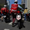 Seorang pria mendorong sepeda motornya dengan masker wajah bergambar Presiden Dewan Perwakilan Rakyat Brasil, Hugo Motta, terpasang selama protes para pekerja pengiriman barang untuk perbaikan kondisi kerja dan menentang rancangan undang-undang yang