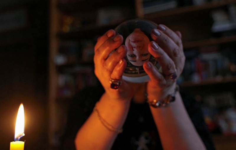 Fortune teller Arina Frants lays out Tarot cards on a table in the voodoo-themed bar Marie Laveau in Moscow, Russia February 17, 2026. REUTERS/Shamil Zhumatov