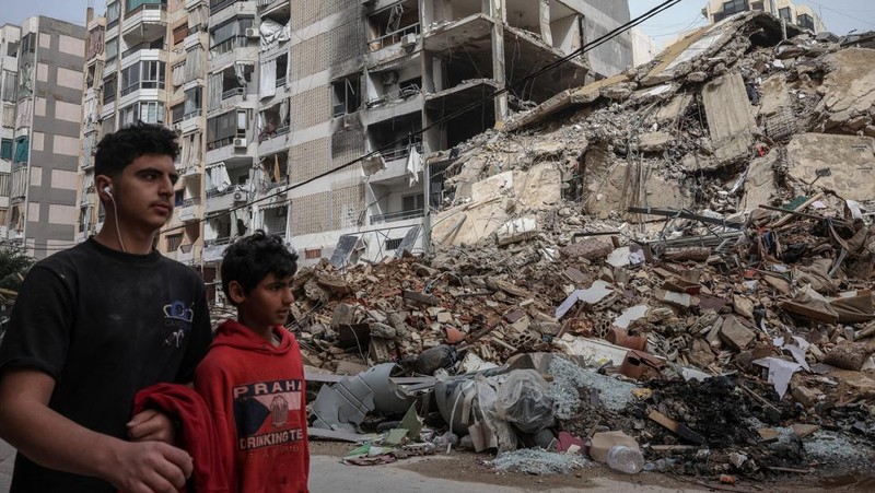 Pasukan penjaga perdamaian PBB berjaga-jaga saat para pengungsi kembali ke rumah mereka menyeberangi jembatan yang menghubungkan Lebanon selatan dengan bagian negara lainnya, yang sebelumnya dihantam serangan Israel, setelah gencatan senjata 10 hari antara Lebanon dan Israel mulai berlaku, di Qasmiyeh, Lebanon, 18 April 2026. (REUTERS/Louisa Gouliamaki)