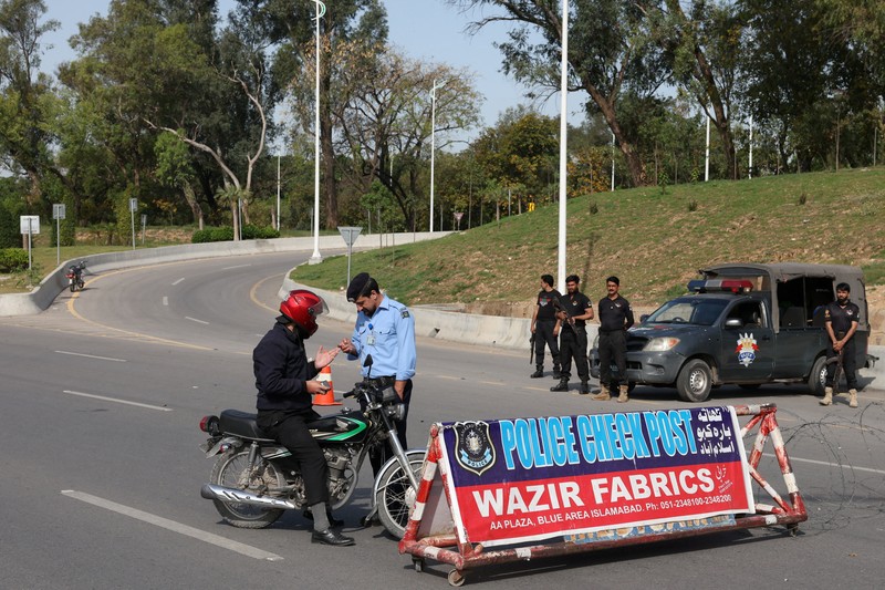 Seorang petugas polisi memberi isyarat ke sebuah kendaraan di pos pemeriksaan di sepanjang jalan dekat Masjid Faisal, saat Pakistan bersiap menjadi tuan rumah bagi AS dan Iran untuk fase kedua pembicaraan perdamaian di Islamabad, Pakistan, 19 April 2026. (REUTERS/Akhtar Soomro)