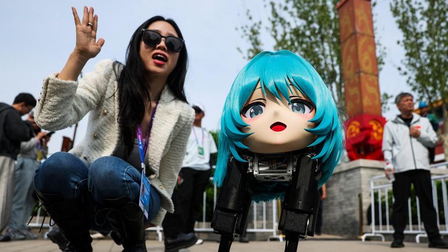 Seorang wanita bereaksi saat duduk di sebelah robot di area penonton pada ajang Beijing E-Town Half Marathon dan Humanoid Robot Half Marathon kedua di Beijing, China, 19 April 2026.