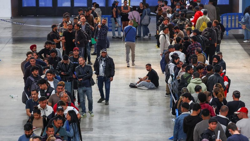 Orang-orang mengantre untuk menerima dokumen saat proses regularisasi migran massal Spanyol akan dimulai, di Hospitalet de Llobregat, dekat Barcelona, ​​Spanyol, 20 April 2026. REUTERS/Albert Gea
