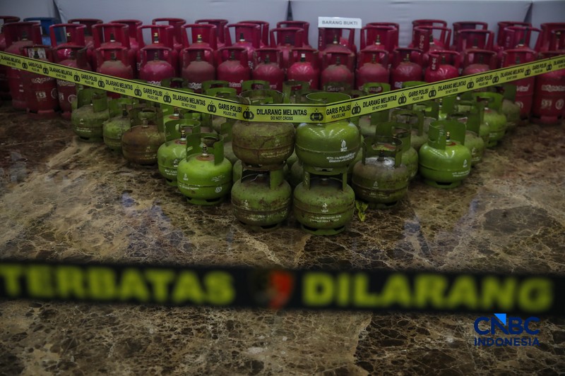Petugas memasang garis polisi pada barang bukti saat konferensi pers Pengungkapan Kasus Penyalahgunaan BBM dan Elipiji Subsidi di Bareskrim Polri, Jakarta, Selasa (21/4/2026). (CNBC Indonesia/Faisal Rahman)