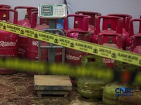 Petugas memasang garis polisi pada barang bukti saat konferensi pers Pengungkapan Kasus Penyalahgunaan BBM dan Elipiji Subsidi di Bareskrim Polri, Jakarta, Selasa (21/4/2026). (CNBC Indonesia/Faisal Rahman)