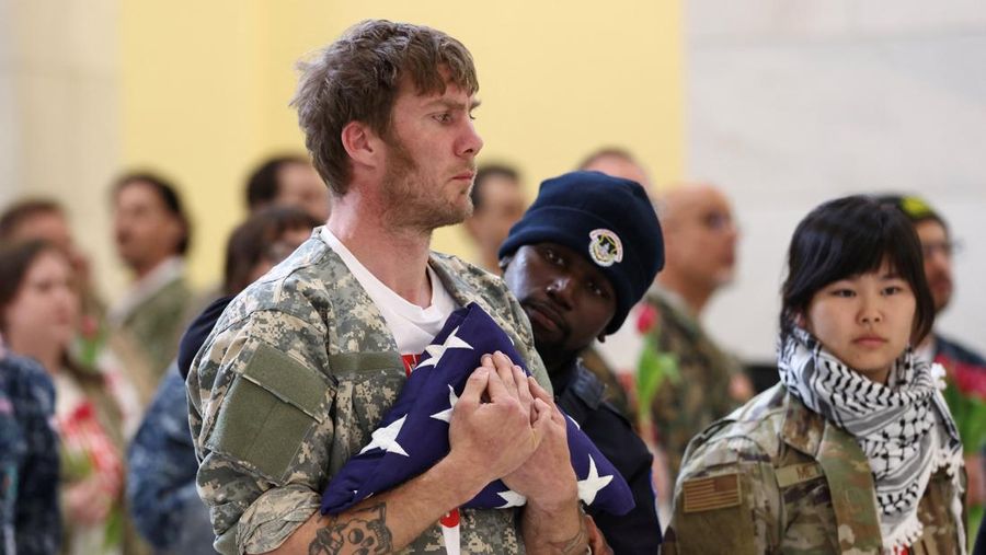 Seorang veteran dari kelompok About Face memegang bendera pemakaman simbolis untuk menghormati orang mati saat polisi menangkapnya selama protes menentang perang Iran, di Rotunda Gedung Kantor Cannon House di Capitol Hill di Washington, D.C., AS, 20 April 2026.