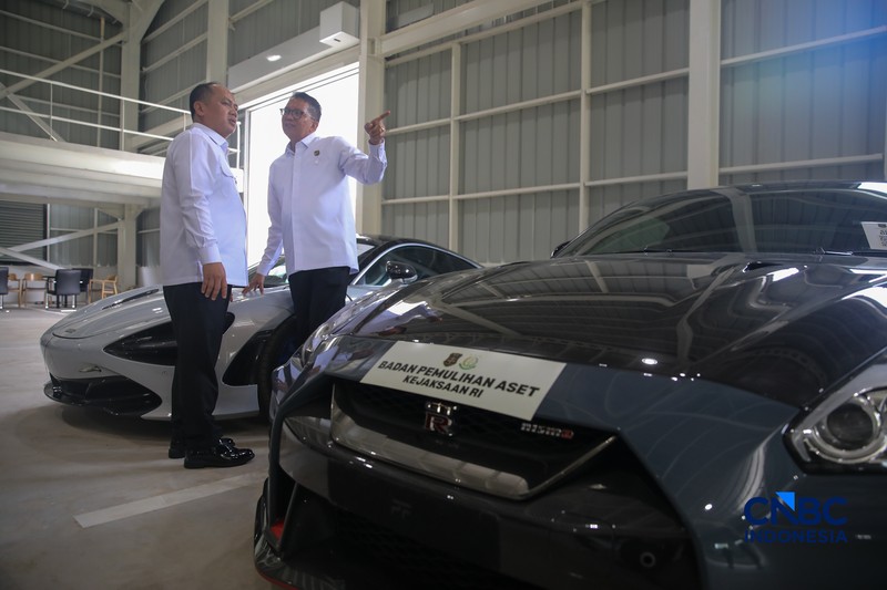 Petugas meninjau mobil sitaan Kejaksaan Agung (Kejagung) yang terparkir di kantor Badan Pemulihan Aset (BPA) Kejagung RI, Jakarta, Rabu (22/4/2026). (CNBC Indoneisa/Faisal Rahman)