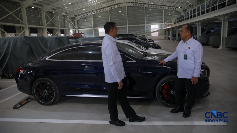 Petugas meninjau mobil sitaan Kejaksaan Agung (Kejagung) yang terparkir di kantor Badan Pemulihan Aset (BPA) Kejagung RI, Jakarta, Rabu (22/4/2026). (CNBC Indoneisa/Faisal Rahman)