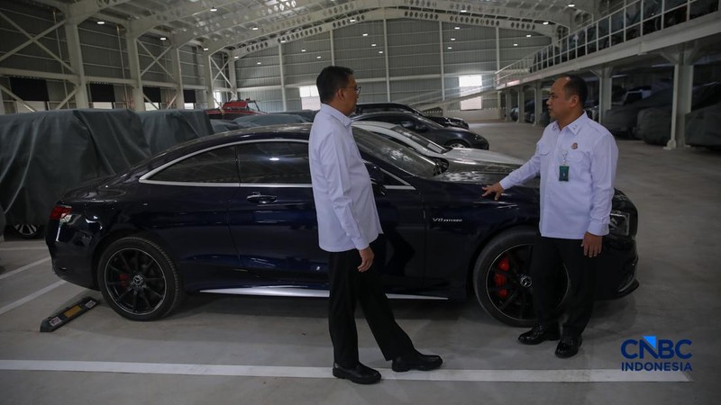 Petugas meninjau mobil sitaan Kejaksaan Agung (Kejagung) yang terparkir di kantor Badan Pemulihan Aset (BPA) Kejagung RI, Jakarta, Rabu (22/4/2026). (CNBC Indoneisa/Faisal Rahman)