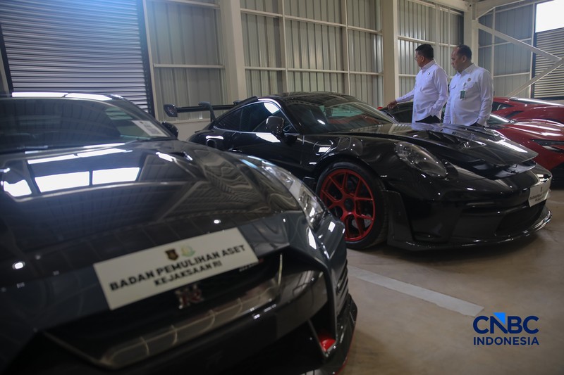 Petugas meninjau mobil sitaan Kejaksaan Agung (Kejagung) yang terparkir di kantor Badan Pemulihan Aset (BPA) Kejagung RI, Jakarta, Rabu (22/4/2026). (CNBC Indoneisa/Faisal Rahman)