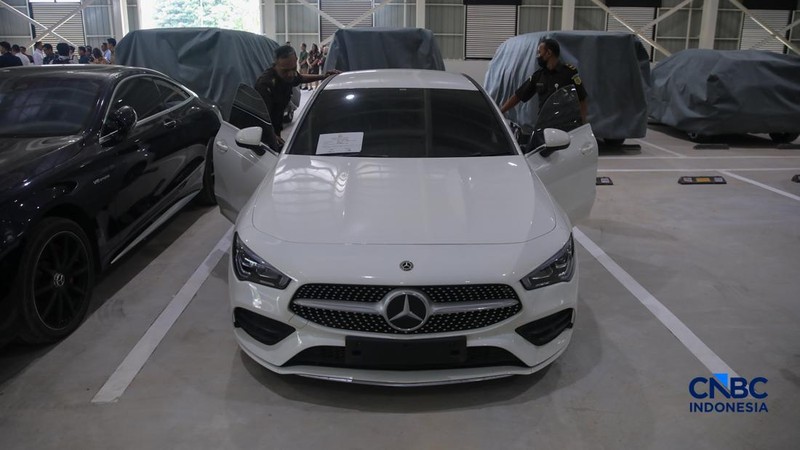 Petugas meninjau mobil sitaan Kejaksaan Agung (Kejagung) yang terparkir di kantor Badan Pemulihan Aset (BPA) Kejagung RI, Jakarta, Rabu (22/4/2026). (CNBC Indoneisa/Faisal Rahman)