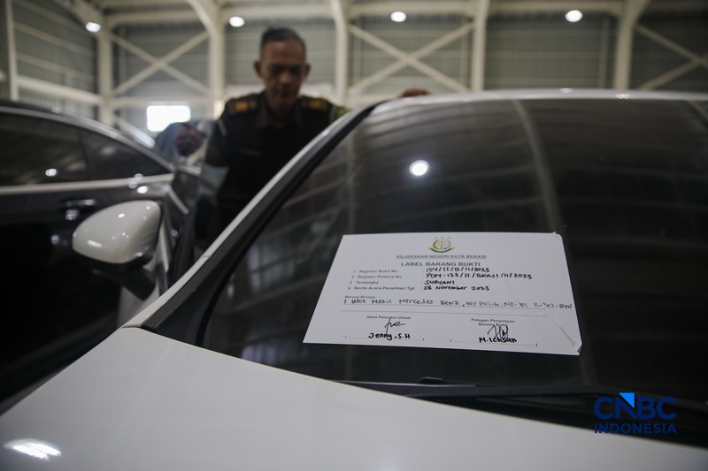 Petugas meninjau mobil sitaan Kejaksaan Agung (Kejagung) yang terparkir di kantor Badan Pemulihan Aset (BPA) Kejagung RI, Jakarta, Rabu (22/4/2026). (CNBC Indoneisa/Faisal Rahman)