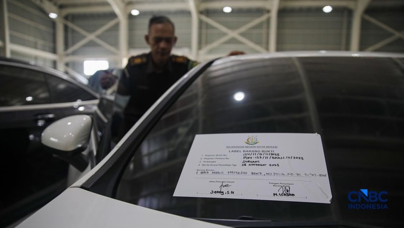 Petugas meninjau mobil sitaan Kejaksaan Agung (Kejagung) yang terparkir di kantor Badan Pemulihan Aset (BPA) Kejagung RI, Jakarta, Rabu (22/4/2026). (CNBC Indoneisa/Faisal Rahman)